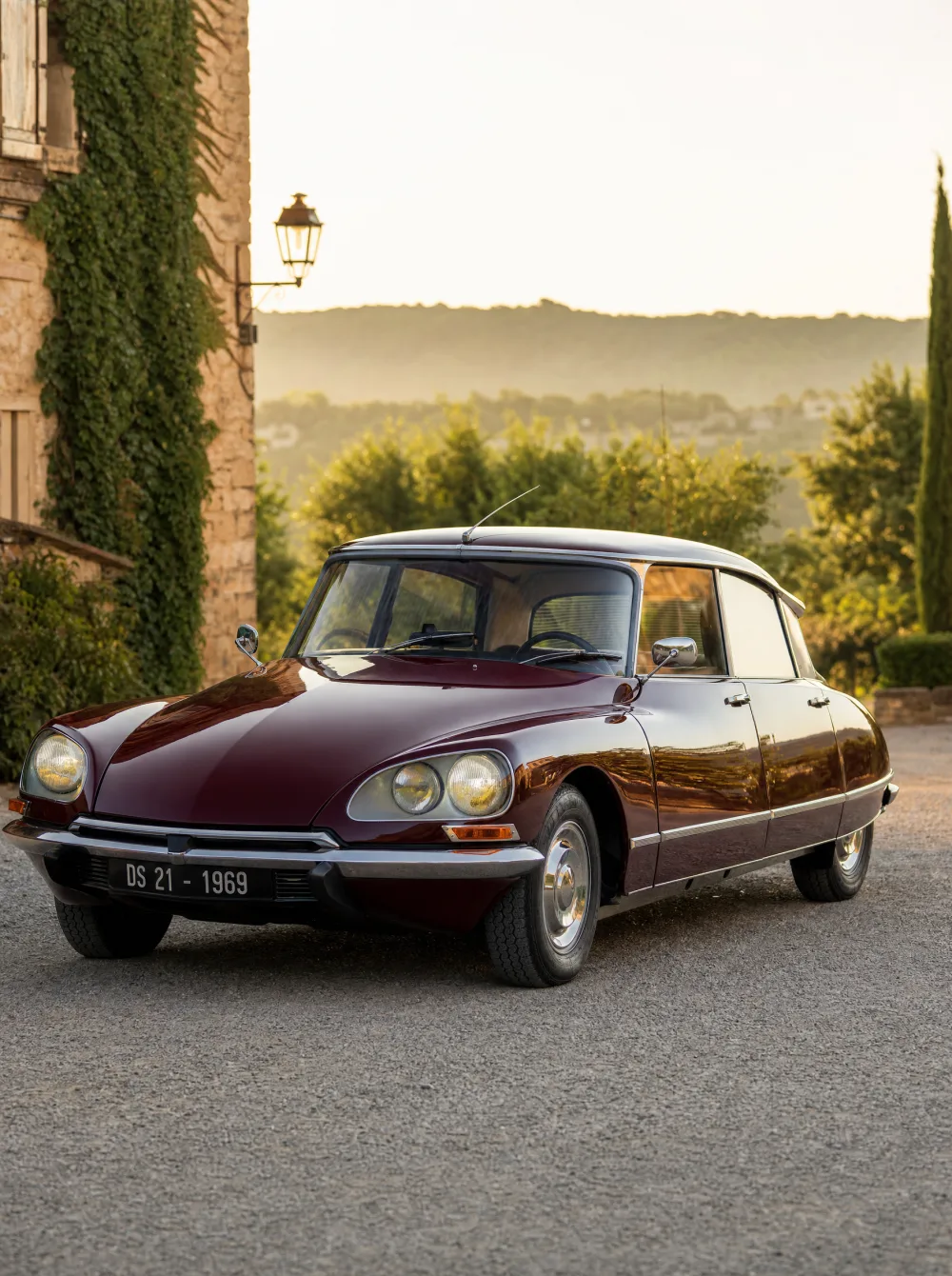 Klassieke Citroën DS 21 uit 1969 in donker bordeauxrood, driekwart vooraanzicht in gouden ochtendlicht.